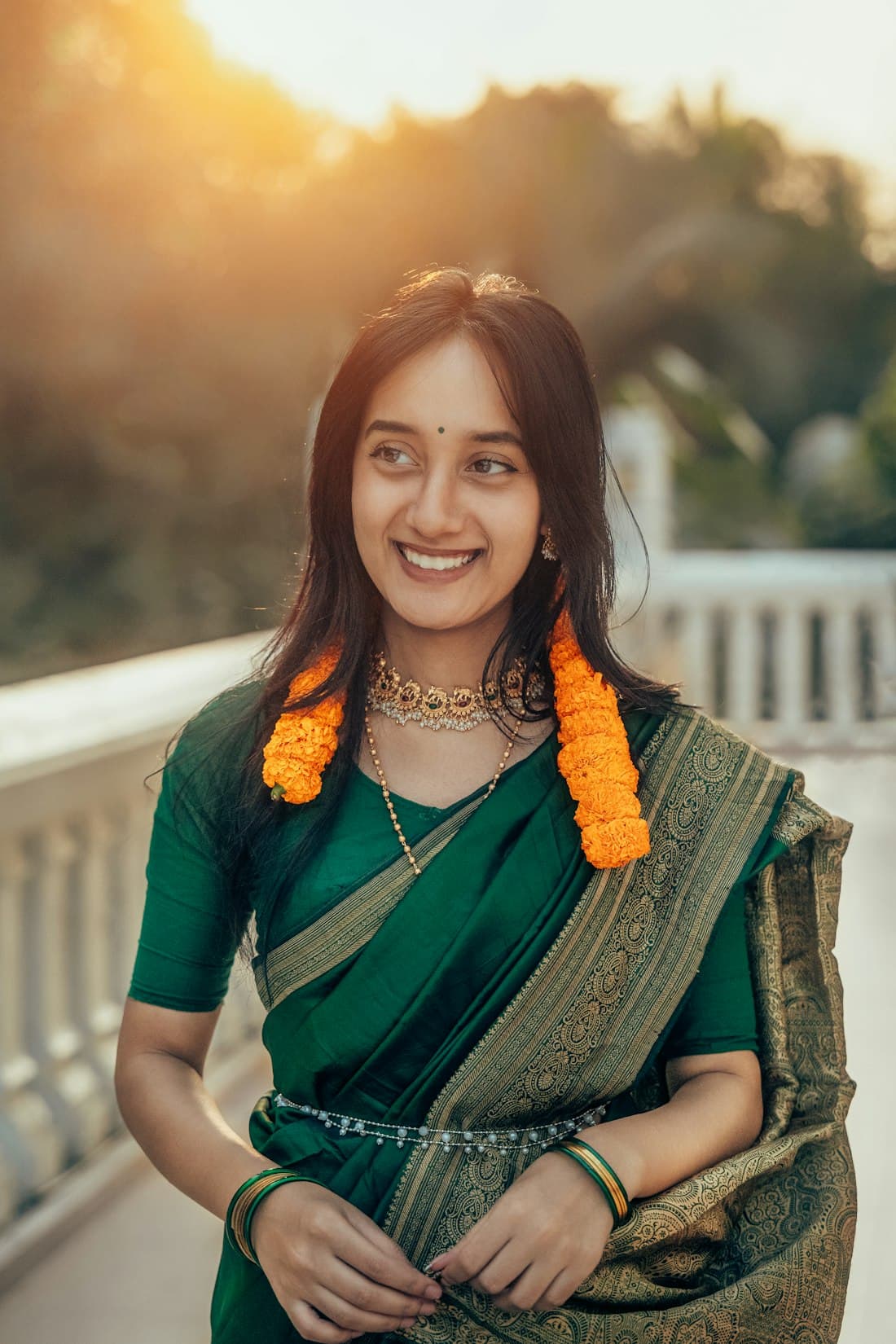 Woman in a green silk saree with marigold garland